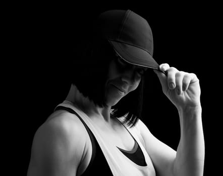portrait of an adult girl with black hair holding a cap on her head, black and white toning