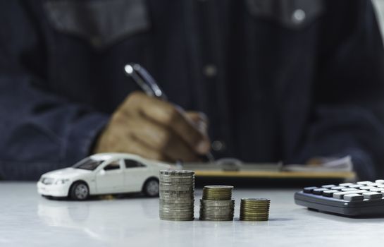 Car insurance and car service. Businessman with stack of coins and toy car, business and financial concept.