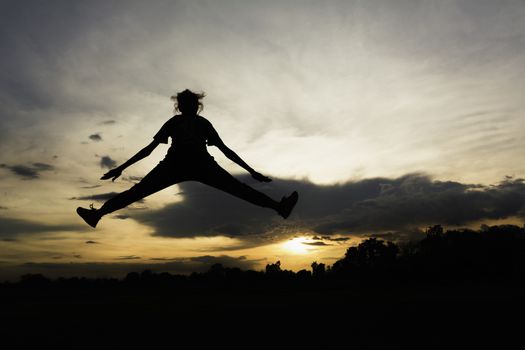 Silhouette of cheerful positive and full energy girl jumping in the air for life energy concept.