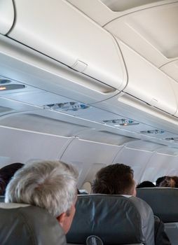 Blurred photo of the aircraft interior. The ceiling of the airplane with luggage compartment