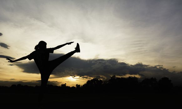 Silhouette of young woman practicing yoga outdoor. Female happiness. Sport and healthy concept. 