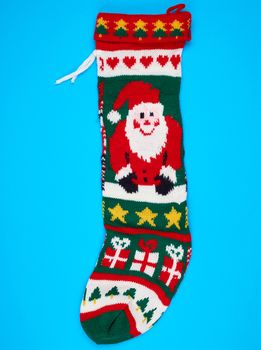 knitted brightly colored Christmas sock for gifts on a blue background, holiday backdrop