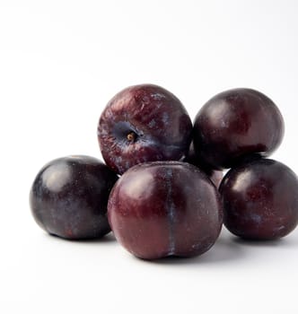 bunch of ripe fresh blue round plums on a white background, summer harvest