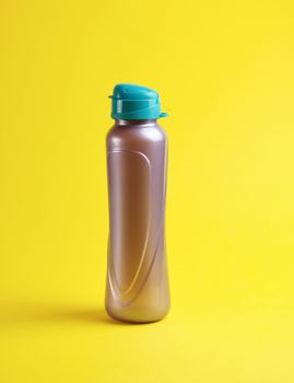 closed plastic sports bottle on a yellow background, close up