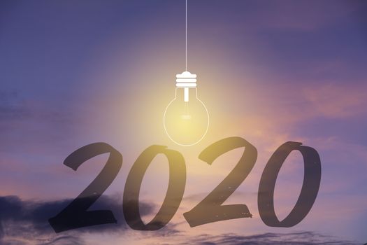 2020 Happy new year numbers with light bulb on sunset sky background