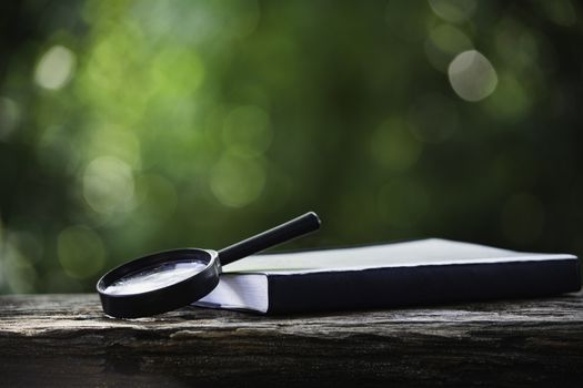 Magnifying glass and book on wooden table and copy space for insert text.