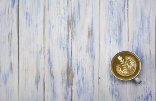 A cup of coffee on wooden table. Top view of coffee latte art with copy space. Drink and art concept.