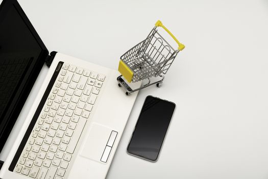 Office desk, computer with smart phone and shopping cart  isolated on white background for technology and business concept.