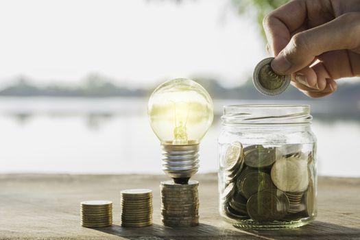 Saving money concept and hand putting money coin in the glass jar for financial and accounting concept.