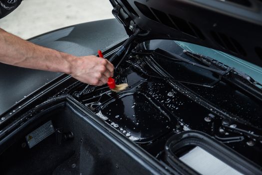 Detailer using a brush on a car during washing