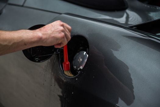 Detailer using a brush on a car during washing