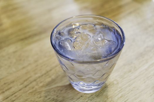 Ice cold water in glass on wooden table with copy space. Drink and healthy concept.