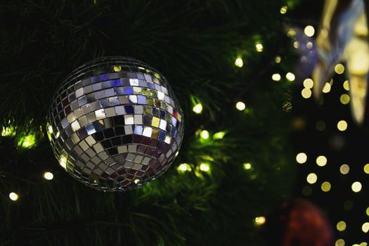 Christmas tree with Decorative lights and mirror ball on blurred background.