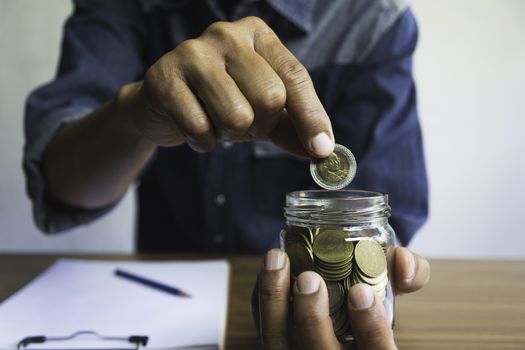 Hand drop a coin in glass jar for business. Financial and accounting concept.