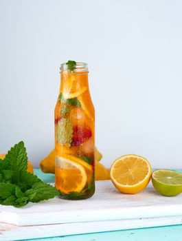 summer refreshing drink lemonade with lemons, cranberry, mint leaves, lime in a glass bottle, next to the ingredients for making a cocktail