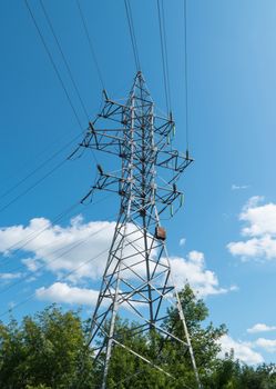 high voltage tower against the blue sky and trees