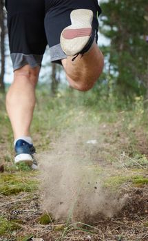 adult man in black shorts runs in the coniferous forest, concept of a healthy lifestyle and running in the fresh air