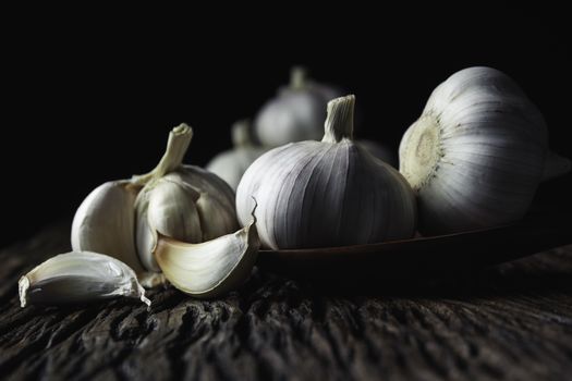 Fresh white garlic on wooden table with black background. Food and healthy concept. 