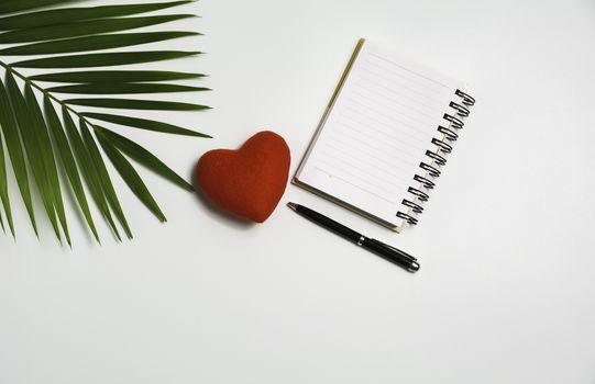 Top view of open book with red heart. Book open with pen on white background.