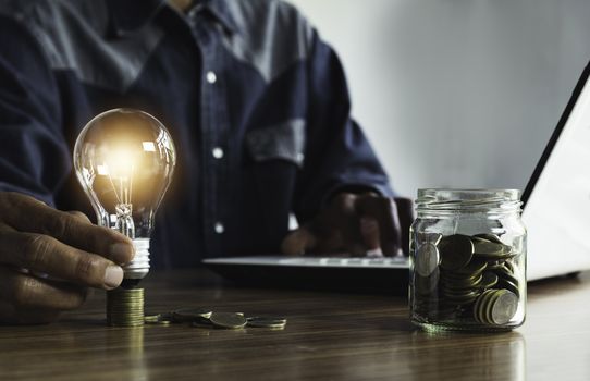 Hand of male holding a light bulb with coins money and copy space for accounting, ideas and creative concept.