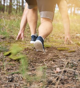 adult man in blue clothes and black shorts runs in the coniferous forest against the bright sun,  concept of a healthy lifestyle and running in the fresh air