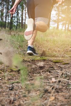 adult man in black shorts runs in the coniferous forest against the bright sun,  concept of a healthy lifestyle and running in the fresh air