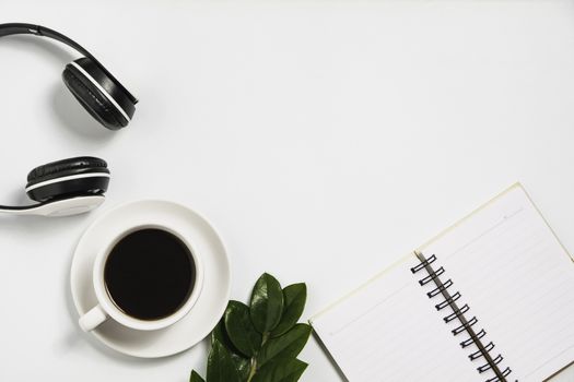 A coffee cup with note and headphone on white desk with copy space.