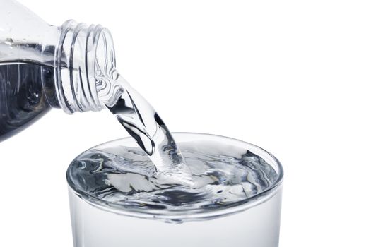 Pouring water from bottle into the glass with clipping path isolated on a white background.