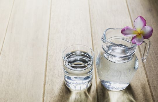 Water glass with glass jar on wooden table. Glass and clean drinking water with copy space.