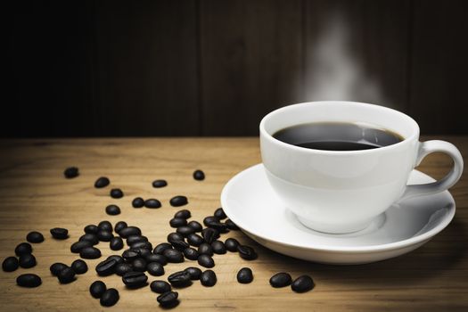 Wooden table desk with coffee. Coffee beans and coffee cup on wooden background with copy space.