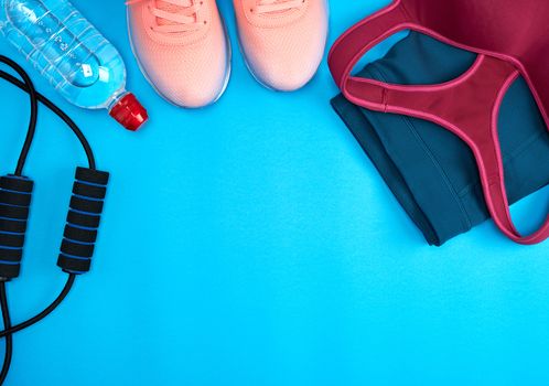 women's sportswear for active sports and pink sneakers on a blue background, top view