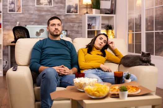 Couple cheering for their favourite team while watching TV and eating fast food