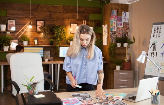 Female dressmaker in creative office checking her ideas. Assistant in the background.