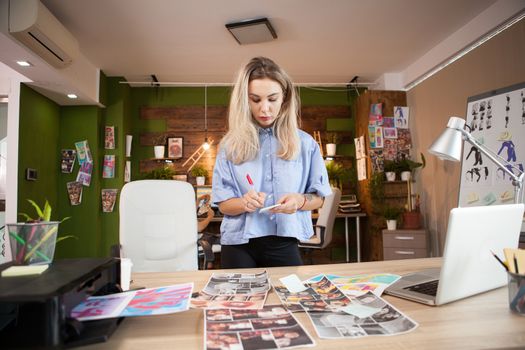 Young caucasian fashion designer working on her designs in creative office.