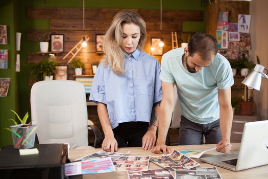 Designers working together at desk in modern office to create a fashionable dress line.