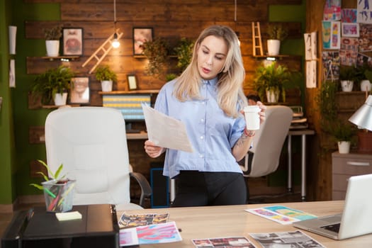 Concentrated female designer holding a paper with creative design.