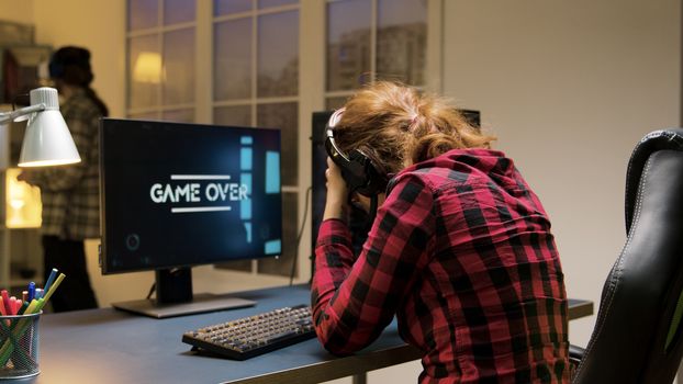 Game over for a professional caucasian female gamer sitting on gaming chair. Man wearing vr headset.