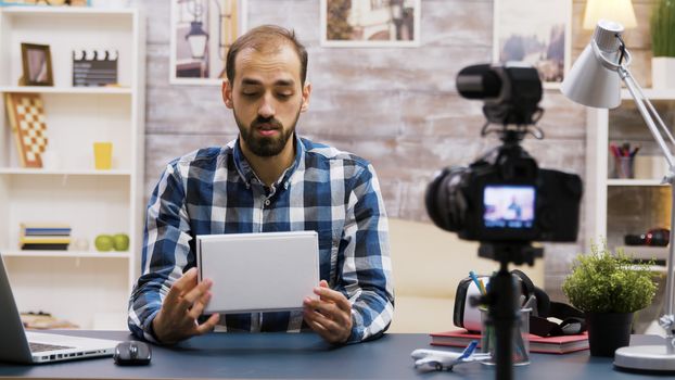 Handsome bearded vlogger recording a review while holding a box. Online content creator.