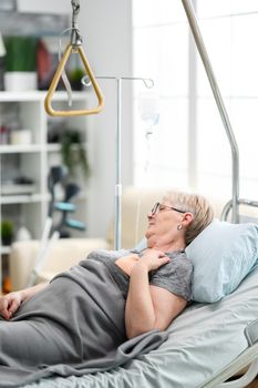 Caucasian old woman in a nursing home with health problems laying on bed.