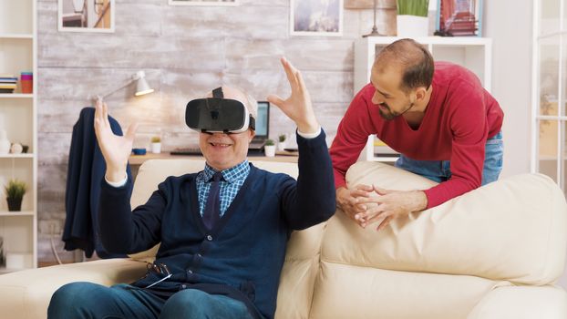 Nephew showing his grandfather how to use VR headset in living room.