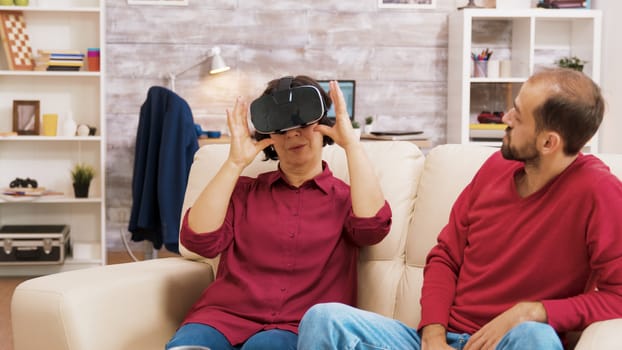 Nephew teaching his grandmother how to use virtual reality headset in living room