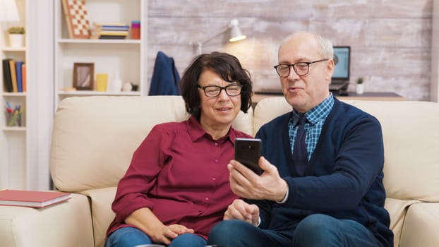 Old man and woman having a video call using their smartphone. Elderly couple using modern technology