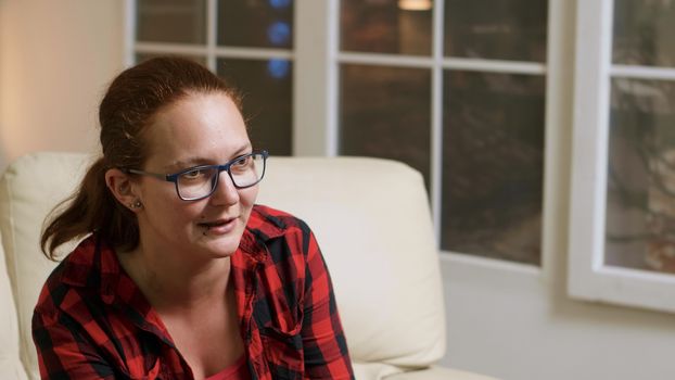 Close up of woman with glasses playing video games sitting on sofa.