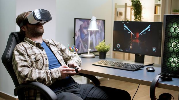 Bearded man sitting on gaming chair playing games using vr headset. Woman in the background.