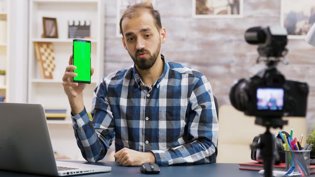 Young and famous influencer filming a review of a phone with green screen. Creative content creator.