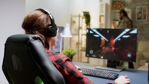 Red headed woman upset she lost while playing shooter games on computer. Female sitting on gaming chair.