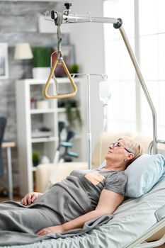 Retired old woman lying peacefully in a nursing home bed. Aged granny in nursing home.