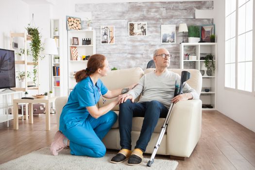 Pretty nurse trying to get old man attention in nursing home. Old man with crutches.