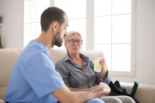 Senior woman in nursing home taking her pills and talking with male nurse.