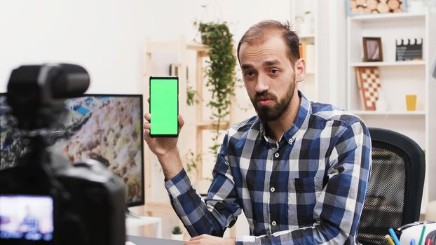 Attractive influencer recording review of phone with green screen. Famous vlogger.